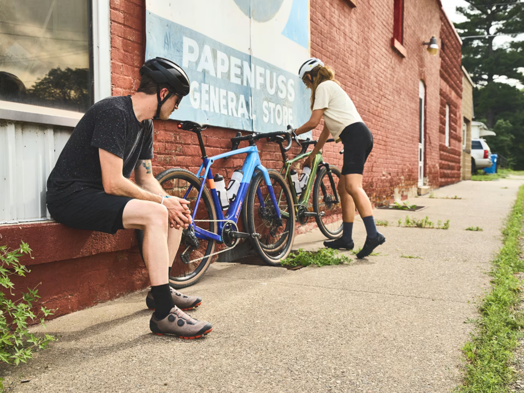 Two cyclists wearing helmets beside their bicycles